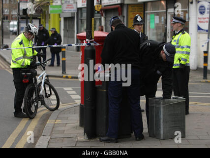 L'uomo ha sparato morto nel sud di Londra. Gli ufficiali di polizia cercano un bidone mentre indagano sulla scena di un omicidio su Coldharbour Lane, nel sud di Londra. Foto Stock
