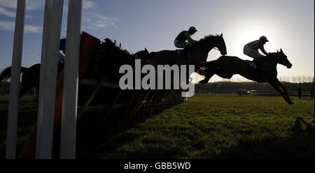 Corridori e corridori saltano l'ultima recinzione la prima volta intorno nel primo grande ostacolo della Maiden occidentale all'Ippodromo di Newbury, Berkshire. Foto Stock