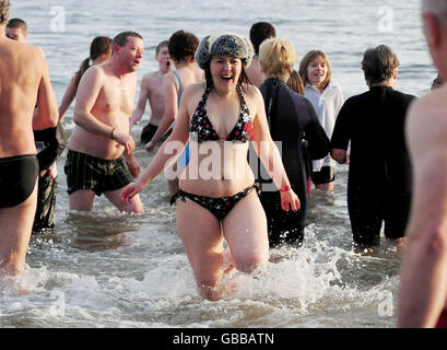 I nuotatori sfidano le temperature gelide di Whitley Bay Northumberland per un tuffo di Capodanno nel Mare del Nord. Foto Stock