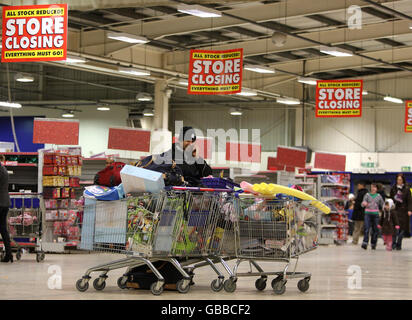 Un negoziatore con carrelli pieni di merci dall'ultimo giorno di negoziazione presso il negozio Woolworths di Edimburgo. Foto Stock