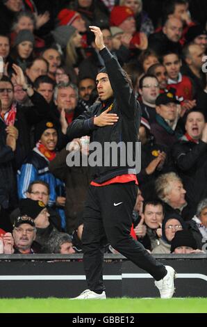 Carlos Tevez di Manchester United fa gesti ai tifosi mentre si riscalda sulla linea di contatto toccando il badge del club il suo top di allenamento
