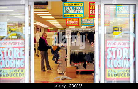 Un cliente esplora alcuni degli ultimi articoli rimasti nel negozio Woolworths di Harrogate, North Yorkshire, l'ultimo giorno di negoziazione per i negozi rimanenti. Foto Stock