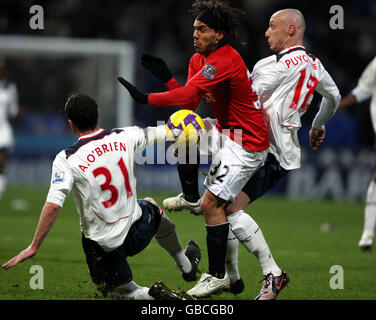 Carlos Tevez (centro) di Manchester United combatte per la palla con Andy o'Brien di Bolton Wanderers e Sebastien Puygrenier Foto Stock