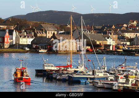 Una vista generale della città di Scalloway sulle Isole Shetland, con turbine eoliche sulla collina dietro. Foto Stock