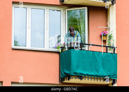 Motala, Svezia - 21 Giugno 2016: Senior uomo misurazione su un balcone. Ha ha un piccolo pezzo di carta in mano come bene. Foto Stock