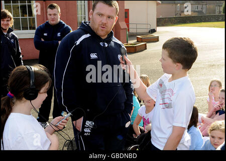 Foto Derek Blair. Internazionale scozzese Allan Jacobsen prende parte a rugby sessione di allenamento a North Queensferry scuola primaria come parte di un programma organizzato da Dunfermline Development Officer Phil Smith(visto tenendo la sessione con parte superiore rossa su).Primary 6/7 gli studenti prenderanno parte a sei settimane del programma whick calci fuori con l'arrivo di prop Jacebson. PIC mostra North Queensferry scuola primaria stazione radio di ottenere un colloquio con il puntello. Foto Stock