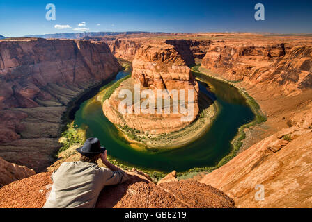 Giovane uomo in una fedora guardando a ferro di cavallo ansa del fiume Colorado vicino a pagina, Arizona, Stati Uniti d'America Foto Stock