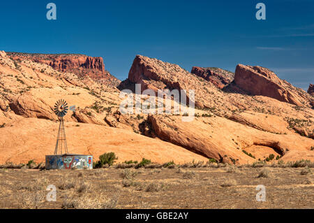 Old Aermotor mulino a vento e serbatoio d'acqua, Skeleton Mesa pietra arenaria alle spalle, Navajo Riserva indiana, vicino Kayenta, Arizona, Stati Uniti Foto Stock