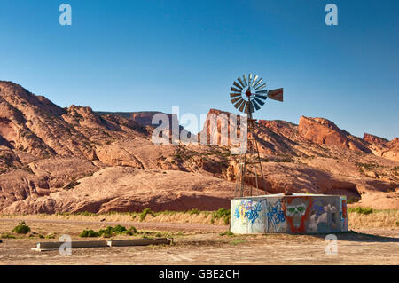 Old Aermotor mulino a vento e serbatoio d'acqua, Skeleton Mesa dietro, Navajo Riserva indiana, vicino Kayenta, Arizona, Stati Uniti Foto Stock