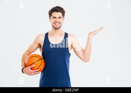 Cheerul giovane sportivo con campi da basket ball azienda copyspace su Palm su sfondo bianco Foto Stock