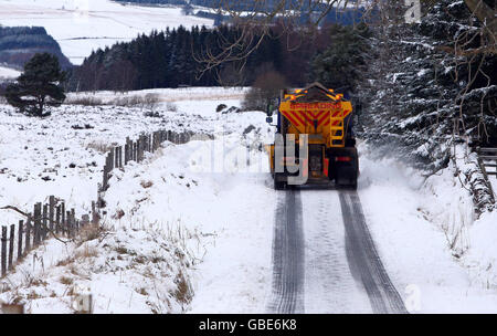 Un gritter innaffia una strada innevata nel Perthshire. Foto Stock