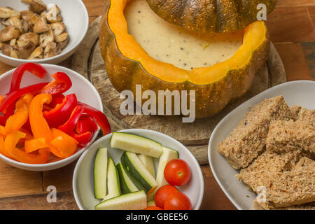 La Fonduta di formaggio in una zucca arrosto con pane e ortaggi assortiti Foto Stock