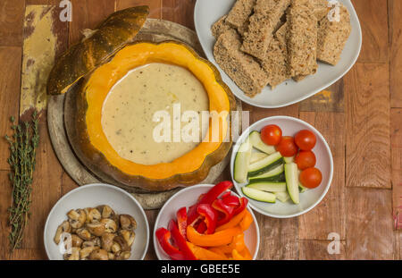 La Fonduta di formaggio in una zucca arrosto con pane e ortaggi assortiti Foto Stock