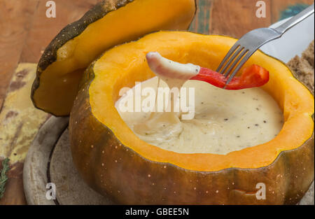 La Fonduta di formaggio in una zucca arrosto con una fetta di peperone su una forcella Foto Stock