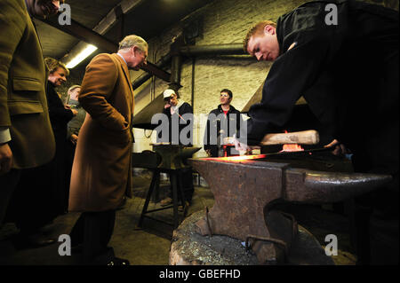 Il Principe del Galles (a sinistra) chiacchiera con gli studenti che studiano il blacksmithing, durante una visita al Centro Rurale di abilità nel Cirencester, Gloucestershire. Foto Stock