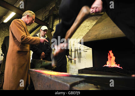 Il Principe del Galles (a sinistra) chiacchiera con gli studenti che studiano il blacksmithing, durante una visita al Centro Rurale di abilità nel Cirencester, Gloucestershire. Foto Stock