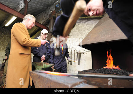 Il Principe del Galles (a sinistra) chiacchiera con gli studenti che studiano il blacksmithing, durante una visita al Centro Rurale di abilità nel Cirencester, Gloucestershire. Foto Stock