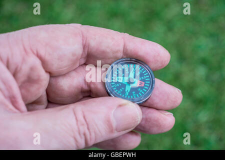 Concetto di direzione di navigazione e sapere dove si sta andando o trovare il vostro modo, illustrata da un hand-held bottone magnetico bussola. Foto Stock