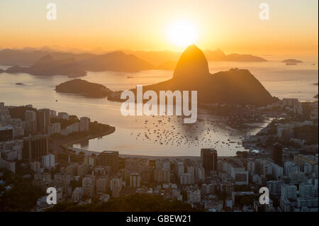 Scenic sunrise a Rio de Janeiro in Brasile incandescente golden sulla baia di Guanabara con uno skyline silhouette di Sugarloaf Mountain Foto Stock