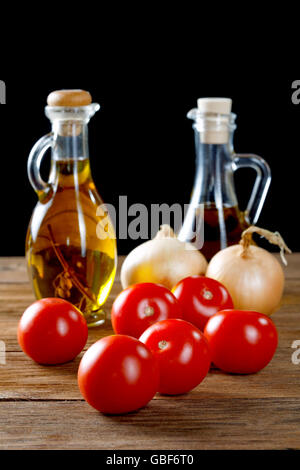 Pomodori e bottiglie di olio d'oliva sul tavolo rustico Foto Stock