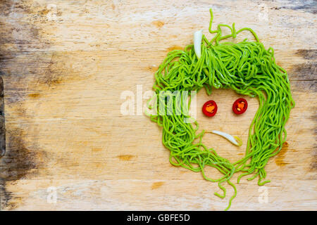 Facce tristi su legno sfondo costituito da grassi vegetali e a base di noodle Foto Stock