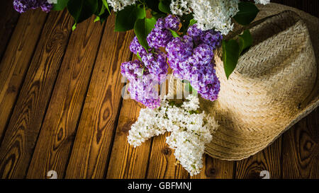 Still-life con un mazzo di lillà e un cappello di paglia, close-up Foto Stock