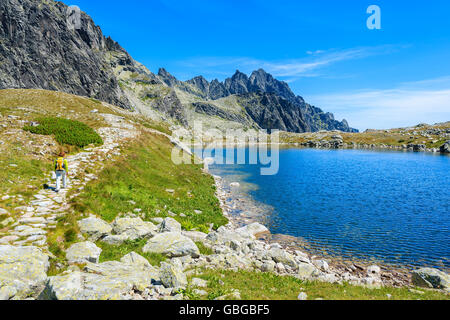 Giovane donna passeggiate turistiche lungo il bellissimo lago alpino in valle Starolesna, Alti Tatra, Slovacchia Foto Stock