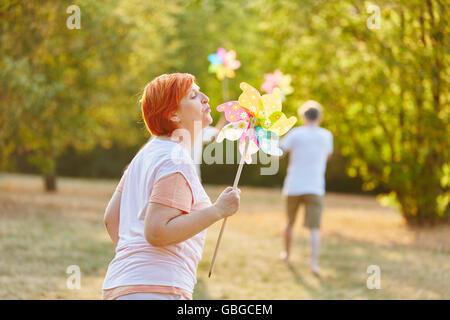 Senior donna che gioca con una girandola in estate nel parco Foto Stock