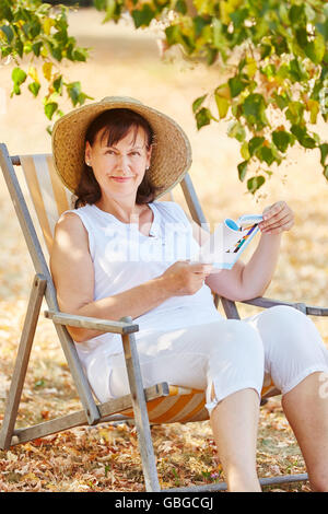 Senior donna relax e lettura in estate in giardino Foto Stock