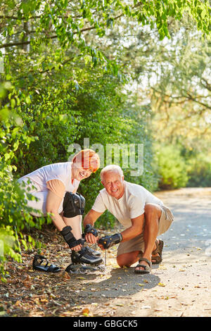 Coppia attiva di anziani ottenere pronto a pattinare nel parco in estate Foto Stock