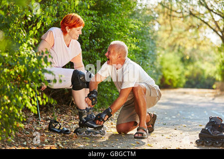 Coppia senior di ridere e prepararsi a pattinare nel parco in estate Foto Stock