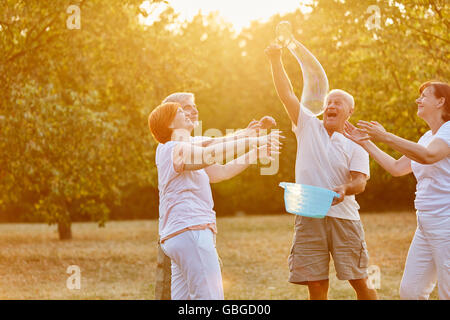 Senior amici divertendosi e rendendo le bolle di sapone nel parco Foto Stock