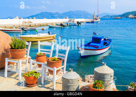 Fioriere su e la vista delle barche da pesca di ancoraggio nel Kokkari bay, Samos Island, Grecia Foto Stock