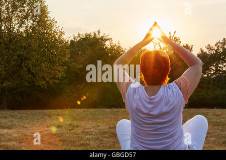 Senior donna fare un esercizio di yoga nella natura in estate Foto Stock