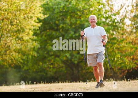 Senior uomo escursioni con racchette nel parco Foto Stock