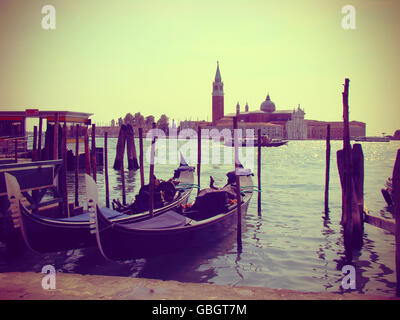 Gondole attraccate in Venezia, vintage tonica. Gondole ormeggiata presso Piazza San Marco. Vista del San Giorgio di maggiore da Piazza Foto Stock