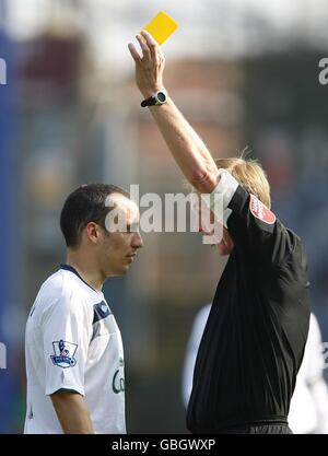 Calcio - Barclays Premier League - Portsmouth / Everton - Fratton Park. L'arbitro Peter Walton (a destra) mostra la León Osman di Everton (a sinistra) una carta gialla Foto Stock