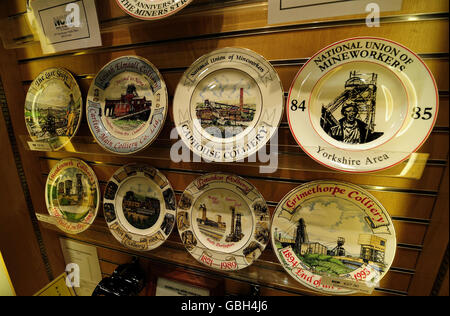 Piatti commemorativi della storia della miniera di carbone, in vendita presso il National Mining Museum presso Caphouse Colliery vicino a Wakefield. Una nuova targa commemorativa del 25° anniversario dello Sciopero dei minatori, iniziato questo mese 25 anni fa (in alto a destra), si erge tra gli altri mostrando i box che si sono chiusi dopo la lunga disputa dell'anno. Foto Stock