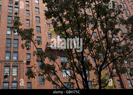 Gli uomini su una finestra di piattaforma di pulizia hanging off il lato del London giardini a terrazza Building a New York, Stati Uniti d'America, 24 aprile 2009 Foto Stock