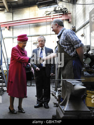 La regina Elisabetta II scuote le mani con un fabbro durante la sua visita alla Whitechapel Bell Foundry, nella parte orientale di Londra. Foto Stock