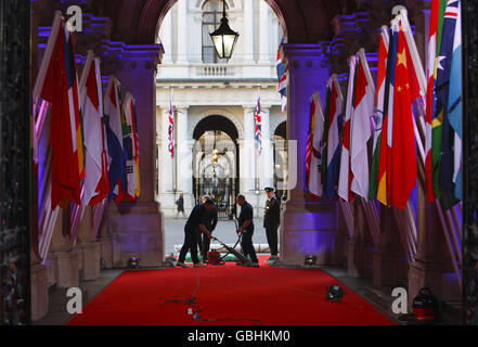 Il personale prepara il tappeto rosso prima che gli ospiti arrivino al 10 di Downing Street per partecipare a una cena prima del vertice del G20. Foto Stock