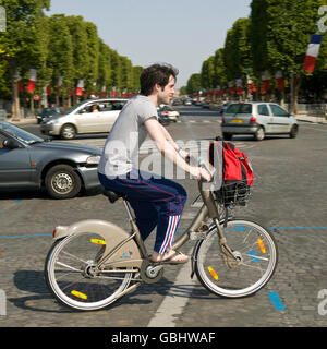 Un uomo che cavalca un Velib' bicicletta attraverso gli Champs Elysees di Parigi, Francia, 15 luglio 2007. Foto Stock