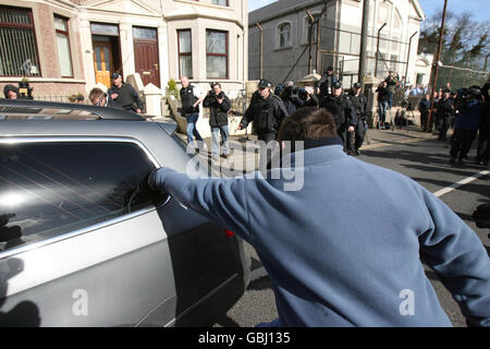 Un protestore punch la polizia auto che porta l'alto profilo repubblicano Colin Duffy come è portato via dalla Larne Court House. Il mese scorso è stato accusato dell'assassinio di due soldati britannici alla Masserine Barracks di Antrim. Foto Stock