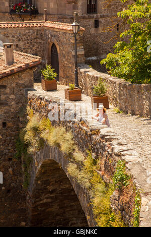 Donna che indossa un cappello di paglia sul ponte medievale di San Cayetano oltre il Fiume Deva nella città di Potes in Picos de Europa Foto Stock