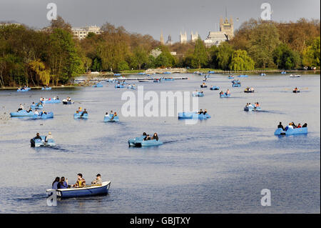 La gente gode del sole del Bank Holiday in pedalò e barche a remi sulla Serpentine nell'Hyde Park di Londra. Foto Stock