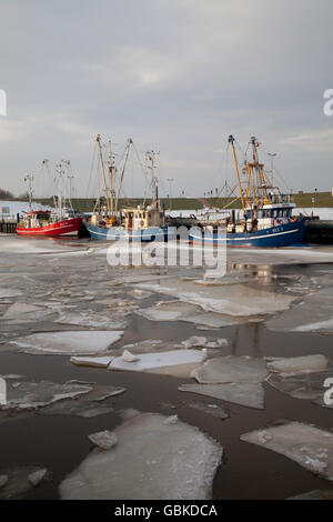 Barche da pesca in porto con ice floes, Dornumersiel, Frisia orientale, Bassa Sassonia, del Mare del Nord Foto Stock