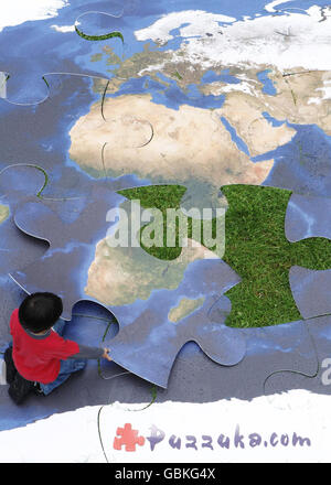 Un bambino mette il tocco finale a un puzzle gigante per il lancio di Puzzle, il più grande sito web di puzzle online del mondo, a Southwark Park, a sud di Londra. Foto Stock