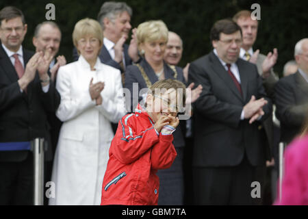 Eamon Cullimore, di sei anni, sorride dopo aver deposto un lilly di Pasqua durante la commemorazione annuale di Fianna Fail 1916 al cimitero di Arbour Hill a Dublino. Foto Stock