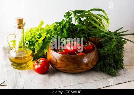 Pomodoro Fresco nella ciotola di legno e olio di oliva. Verdura matura. Verdure fresche. Mangiare sano concetto. Mangiare sano. Piatti vegetariani Foto Stock