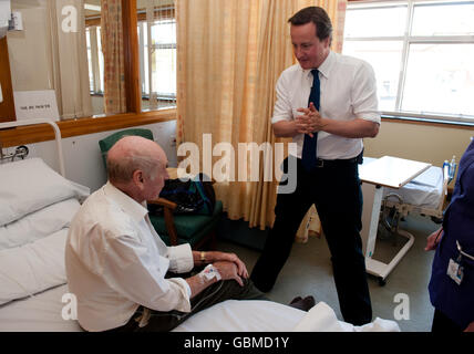 Il leader del Partito conservatore David Cameron parla con il paziente Phillip Lewis durante una visita all'Harrogate District Hospital. Foto Stock